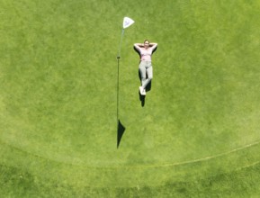 Woman lying on the green at the La Noria Golf Resort. Aerial view. Drone shot. Málaga province,
