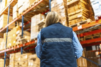 Low angle view of the rear view of a caucasian blonde woman working in a distribution warehouse