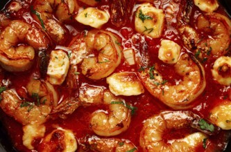 Greek saganaki, in an iron pan, saganaki with shrimp, shrimp in tomato sauce, with pepper and feta