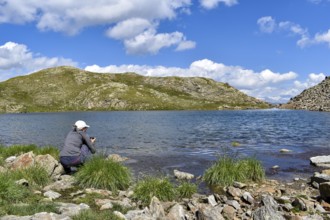 Woman photographing high alpine mountain lake at the Weiße Spitze, in the background the