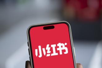 RedNote (Xiaohongshu) logo is displayed on iPhone