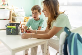 Side view of a concentrated mother and boy doing homework together on the bedroom