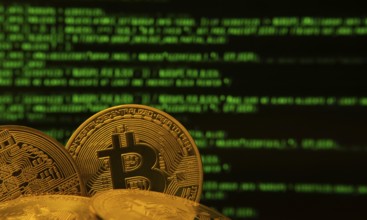 Golden bitcoins in front of green digital code, symbolizing cryptocurrency and technology