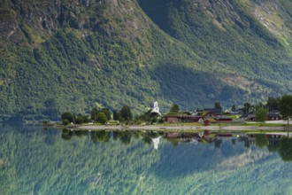 Reflection in lake Oppstrynsvatnet, white stave church, Oppstryn, Stryn, Norwege