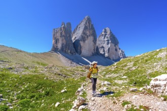 Female tourist walking on the trail leading to the tre cime di lavaredo, enjoying the breathtaking