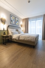 A bright and modern hotel room with a large bed and paintings on the wall, Berlin, Germany