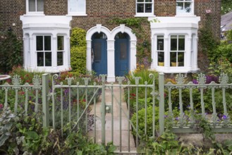 Flower-filled garden, brick house with blue doors, Kew, London, England, Great Britain