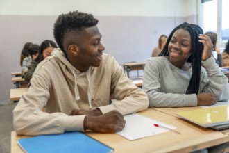 Two college students smiling and engaging in conversation during a lesson, enjoying their time
