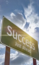 Success just ahead green road sign against a blue sky and clouds