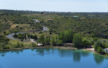 Panorama of a lake with surrounding trees, roads and hills under a clear sky, view from the viewing