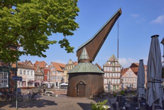 Old crane with outdoor area of a restaurant and historic half-timbered houses in the Hanseatic