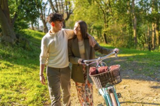 Young couple walking hand in hand through a picturesque park, riding a bicycle and basking in the