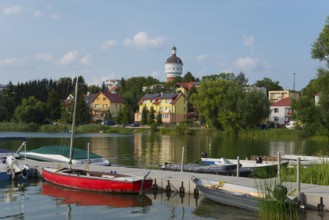 Red boat on the pier with a view of colourful houses and a water tower, summer atmosphere, Elk,