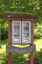 Small, wooden building with windows and an old sign in the countryside, Rügen, Hiddensee