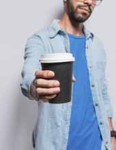 Close up of person offering a coffee to go, Young man offering the camera a coffee to go, Handsome