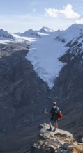 Mountaineer standing on a rock, surrounded by an impressive mountain landscape with snow-covered