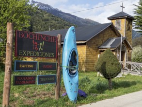 Signpost of tour operator for rafting, kayaking, trekking, next to wooden church, village