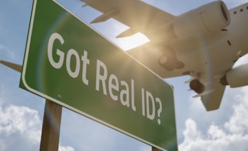 Got real ID? green road sign with low flying airplane just above with landing gear down