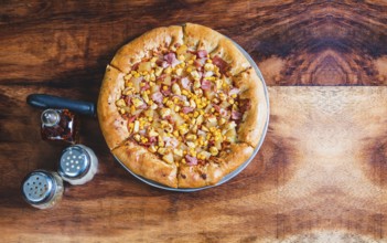 Top view of ham and corn pizza on wooden table. Ham pizza with corn on wooden background