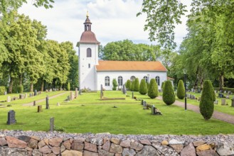 Church with tombstones in the Swedish countryside with lush green trees a summer day, Kättilstorp,