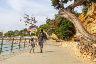 Mother and son enjoying a leisurely stroll along the picturesque seaside promenade in porto cristo,
