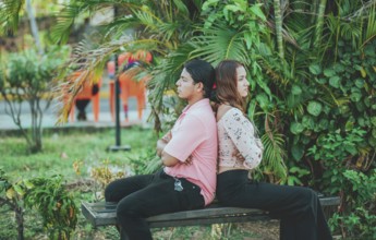 Upset young couple sitting back to back on a bench. Unhappy couple arguing on a public bench.