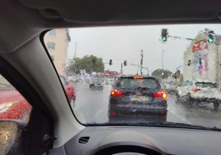 Daytime view from a car in heavy rain with an unclear view of the traffic at a traffic light,