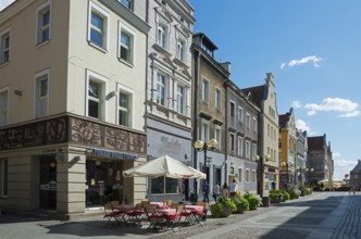 Charming old buildings along a quiet, sunny pedestrianised street with cafés, Old Town, Olsztyn,
