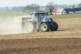 Spring farming, spreading fertilizer with tractor on field in Ystad municipality, Skåne county,