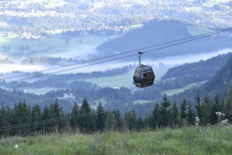 Gondola of the Jennerbahn in front of the valley basin of Berchtesgaden with fog in the early