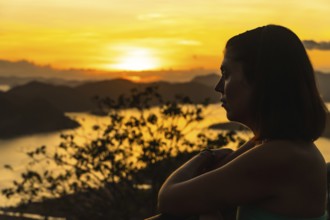 Silhouette of a tourist enjoying a beautiful golden sunset over coron island from mount tapyas