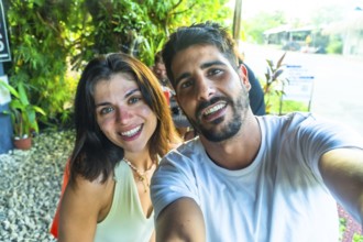 Young couple smiling and taking a selfie during their tropical vacation in siargao island,
