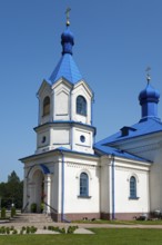 White orthodox church with a striking blue roof, surrounded by nature under a bright sky, Orthodox