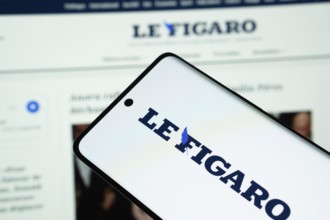 The logo of the newspaper le figaro is displayed on a smartphone screen, and the website le figaro