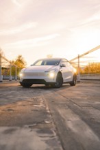 A white car in a city car park in the orange evening light, Tesla new Model Y Juniper, Nagold,