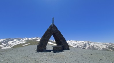 Chapel in a mountainous, snow-covered landscape under a clear blue sky, Virgen de las Nieves,