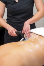 Vertical close-up photo of an unrecognizable massage therapist using the INDIBA machine to relieve