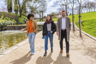 Three young professionals enjoy a walk and talk together during their lunch break in a sunny city