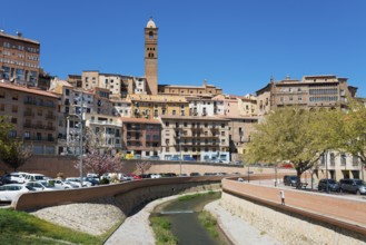 Cityscape with closely spaced houses and a river in the centre, dominated by a tower, church,