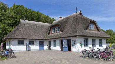 White, traditional thatched roof house with bicycles in front of it under a blue sky, Rügen,