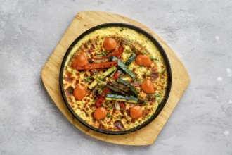 Top view of eggs with bell pepper and zucchini baked in oven in cast-iron skillet