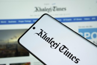 The logo of the newspaper khaleej times is displayed on a smartphone screen, and the website