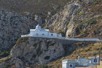 White chapel of Agios Spiridonas with blue roof on a stony rock surrounded by mountains, Menetes,
