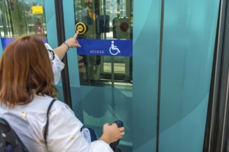 Woman using a wheelchair is pushing accessible button to enter public transport, promoting