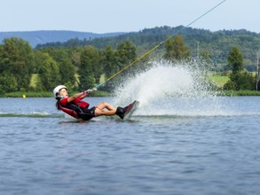 Boy or girl, summer holiday with wakeboard, water splashes, red life jacket, water skiing and