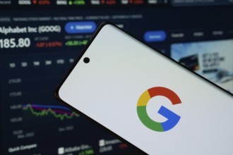 Google logo is displayed on a smartphone screen, with a stock graph webpage visible on a computer