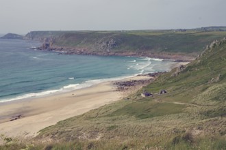 Langer Sandstrand in einer weiten Küstenlandschaft mit klarem Wasser und grünen Hügeln, Rosamunde