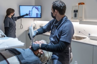 Dentist and assistant performing teeth whitening procedure using innovative 3d scanner technology,