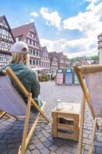 Person on a deckchair with a view of a street full of half-timbered houses, Calw, Black Forest,