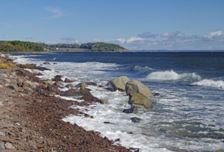 Rocky coast with gentle waves, clear skies and a green coastline, Tönsberg, Oslofjord, Norway